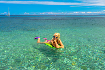 Portrait of woman floating in sea against sky