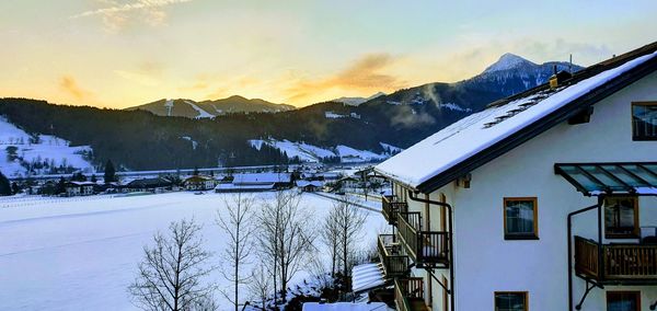 Houses and snowcapped mountains against sky during sunset