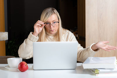 Woman using phone while sitting on table