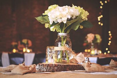 White flowers in jar on tree stump in wedding