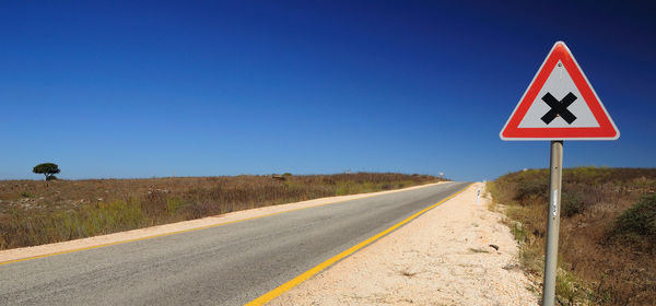 Road sign against clear blue sky