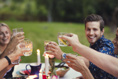Happy friends toasting glasses while enjoying meal at garden party