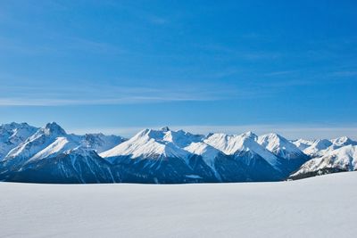 Scenic view of snowcapped mountains against blue sky