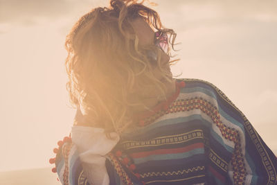 Close-up of woman with hand in hair against sky