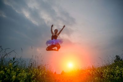 Man jumping in mid-air against sky during sunset