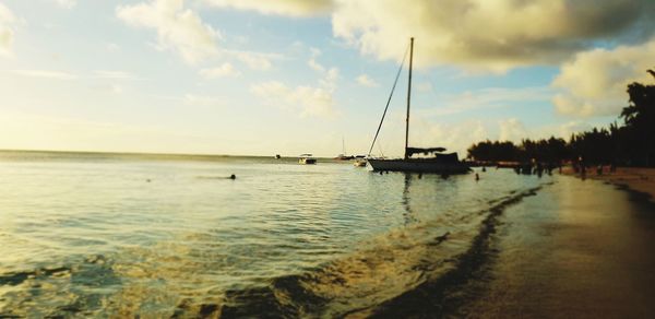 Sailboats in sea against sky during sunset