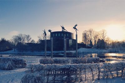 Built structure by lake against sky during sunset