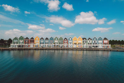 Buildings by river against sky