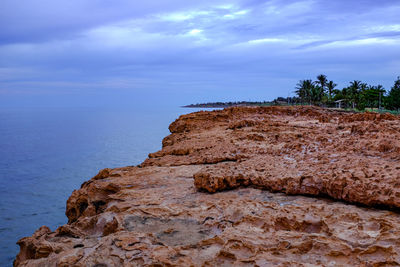 Rock by sea against sky