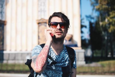 Portrait of young man wearing sunglasses standing outdoors