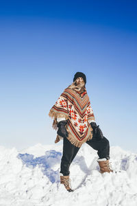 Man with poncho at snow on sunny day