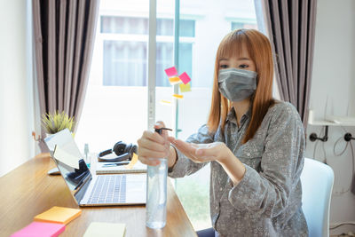 Woman using phone while sitting on table at home