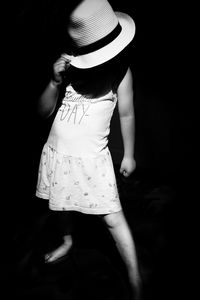 Girl wearing hat while standing against black background
