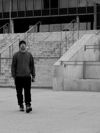 Full length portrait of young man standing against building in city