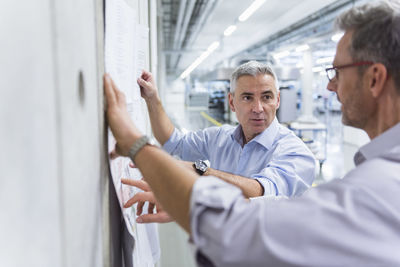 Two businessmen discussing construction plan at concrete wall