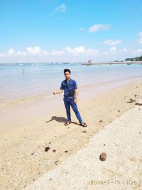 Full length of man standing on beach against sky