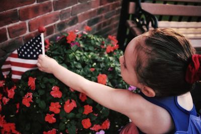 Close-up of girl holding american flag by plants