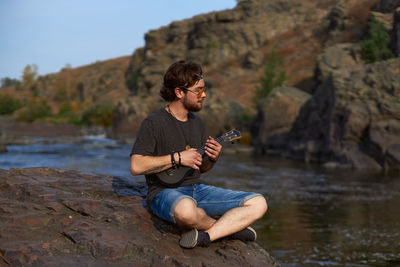 Man sitting on rock by lake