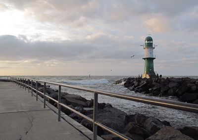 Lighthouse by sea against sky