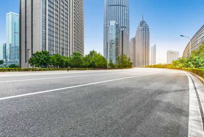 City street by modern buildings against sky