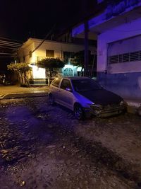 Wet car on illuminated street at night