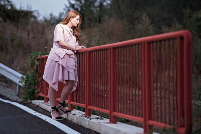 Woman standing by railing against trees