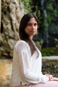 Portrait of young woman sitting on rock