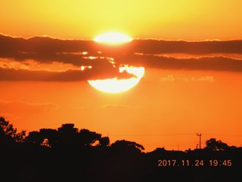 Silhouette trees against dramatic sky during sunset