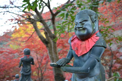 Statue of man standing by plants during autumn