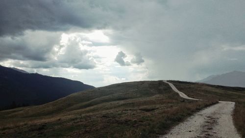 Scenic view of road by mountains against sky