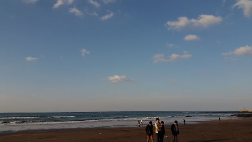 People at beach against sky