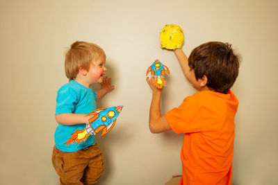 Portrait of boy holding gift against wall