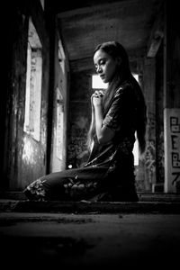 Young woman praying in abandoned building