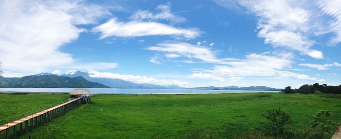 Scenic view of field by lake against sky