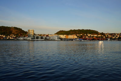 Sea by buildings in town against sky