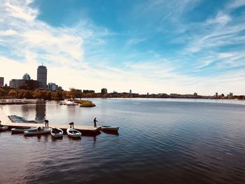 View of boats in river against cloudy sky