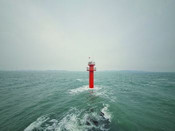 Lighthouse by sea against sky