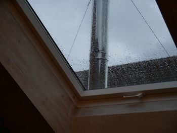 Low angle view of building seen through wet window