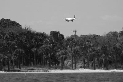 Airplane flying over river against sky