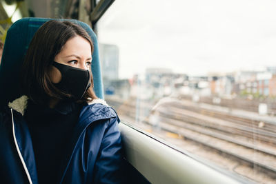 Portrait of beautiful young woman in train wearing a face mask