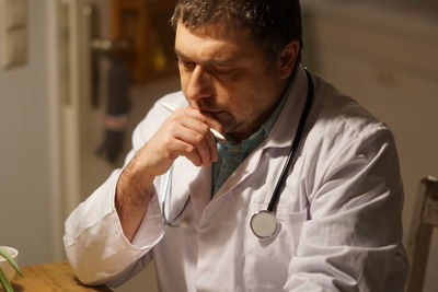 Thoughtful mature doctor with pen working in hospital