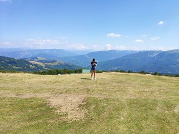 Full length of woman standing on field against mountains