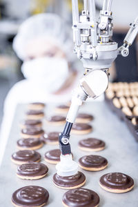 Robot handling cookies with woman in background