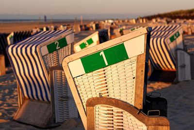 Hooded chairs on table at beach against sky