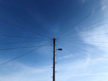 Low angle view of electricity pylon against blue sky