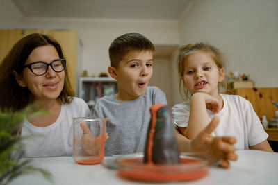 Mom and children at home are conducting an experiment with volcanic eruption.