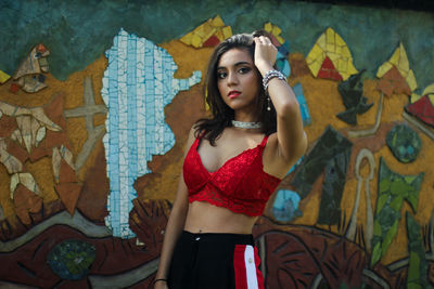 Portrait of beautiful young woman standing against graffiti wall