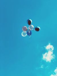 Low angle view of balloons flying against blue sky