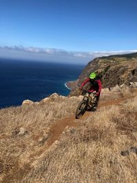 Man riding bicycle on road against sky