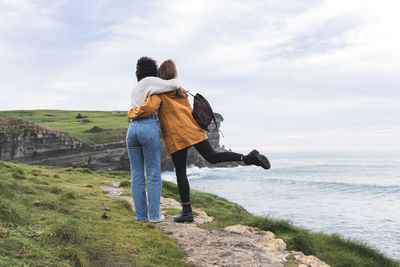 Rear view of couple on shore against sky